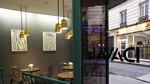 An interior with tables and chairs, artwork on the walls, and a view of the street outside. - Hôtel Daval (Paris)