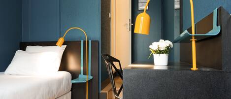 Une chambre d’hôtel moderne avec un lit, un bureau doté d’une lampe, une plante en pot et un escalier.