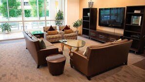 A modern living room with leather sofas, a glass coffee table, and a flat-screen TV. - Crystal Quarters Furnished Apartments- Concord (Arlington)