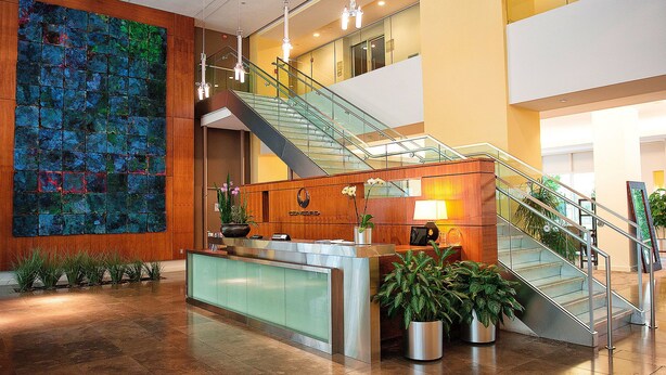A modern lobby with a reception desk, a staircase, and a colorful abstract wall. - Crystal Quarters Furnished Apartments- Concord (Arlington)