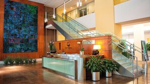 A modern lobby with a reception desk, a staircase, and a colorful abstract wall. - Crystal Quarters Furnished Apartments- Concord (Arlington)