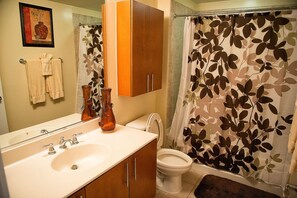 Een badkamer met een wastafel, spiegel, kast, toilet en douchegordijn.