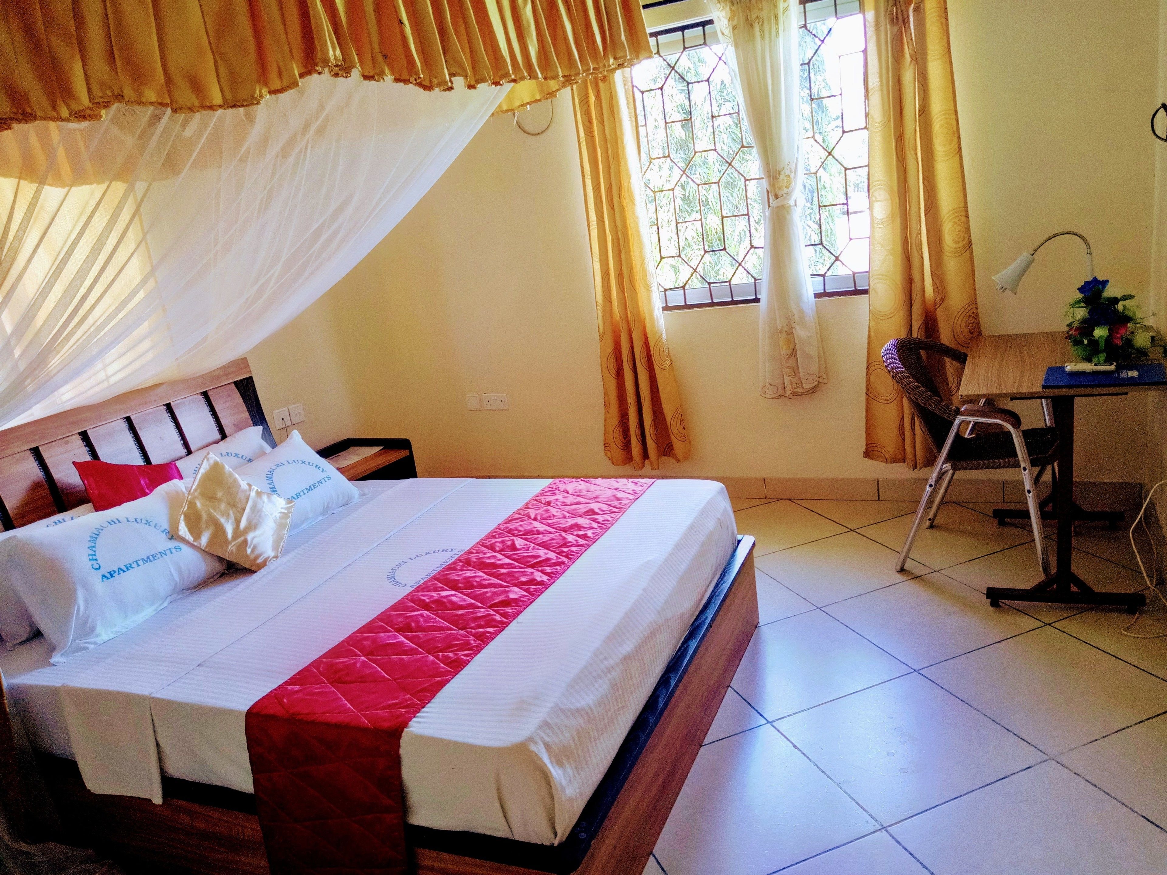 A hotel room with a bed, a desk, and a chair.