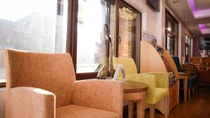 A seating area with cushioned chairs and a small table, a decorative shoe on the table, and a view of the outside through a window.