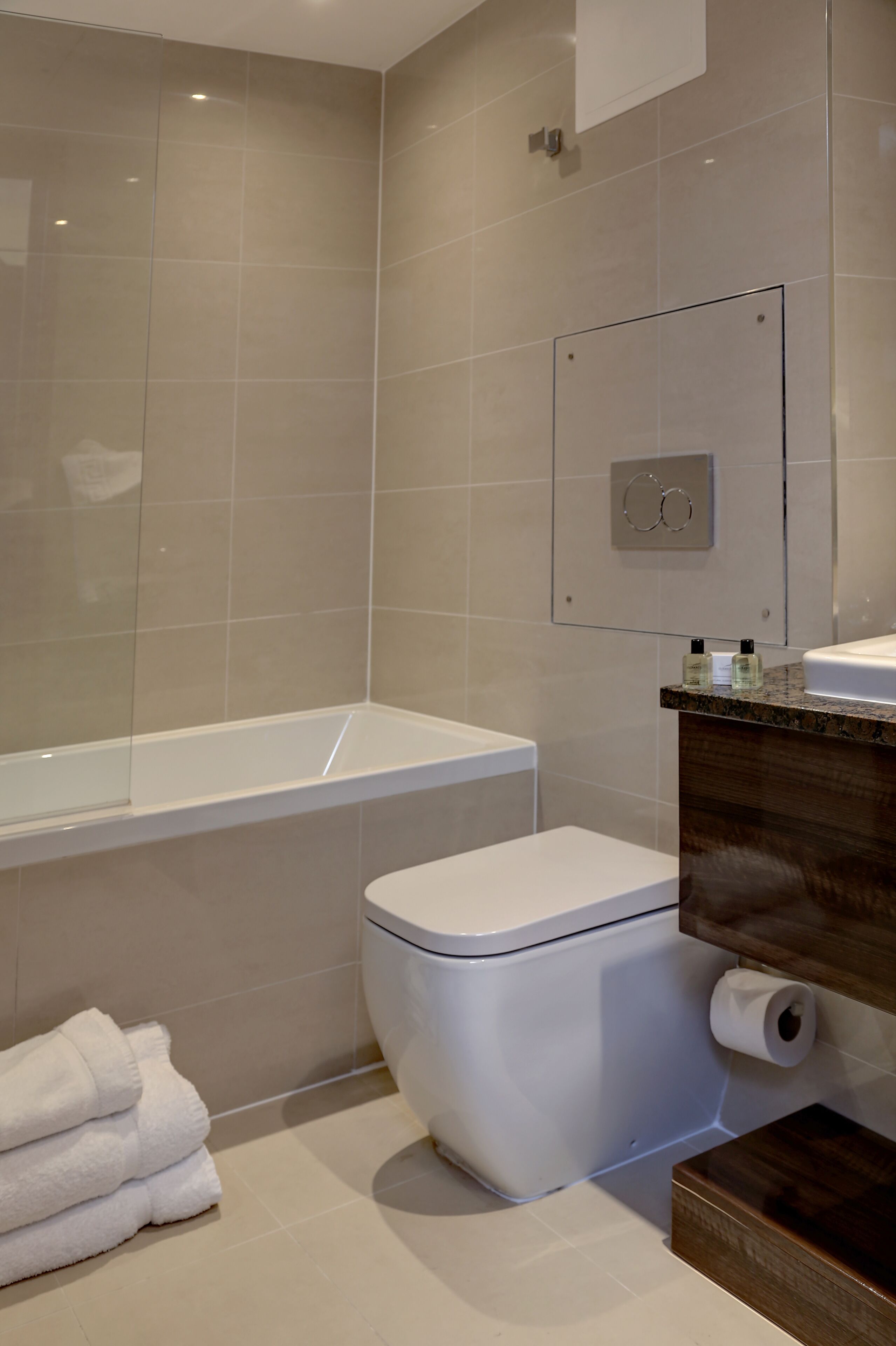 A modern bathroom with a bathtub, toilet, and a vanity with a mirror.