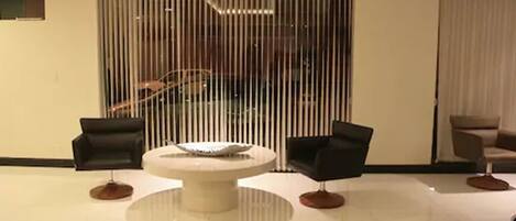 A modern room with a round table, two black chairs, and a wooden floor.