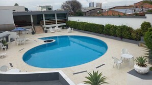 A rooftop pool with a circular shape, surrounded by white lounge chairs and a small table. - Posseidon Hotel (Imperatriz)