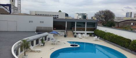 A rooftop swimming pool with lounge chairs and a barbecue area.