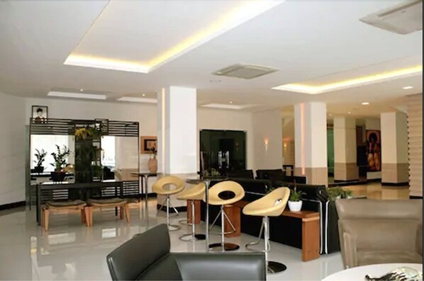 A modern hotel lobby with a reception desk, seating area, and a large flat-screen TV. - Posseidon Hotel (Imperatriz)