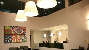 A modern reception area with a black reception desk, two black leather sofas, and a colorful abstract painting on the wall. - Posseidon Hotel (Imperatriz)