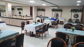 A dining area with multiple tables and chairs, a buffet counter, and ceiling fans.