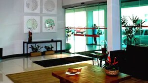 A modern lobby with a wooden coffee table, a black sofa, and three hanging lamps. - Posseidon Hotel (Imperatriz)