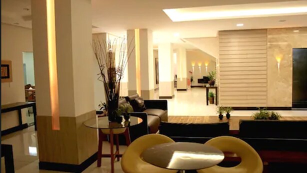 A modern hotel lobby with a seating area, a reception desk, and a television. - Posseidon Hotel (Imperatriz)
