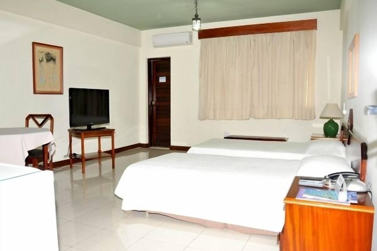 A hotel room with two beds, a TV, a desk, and a door.