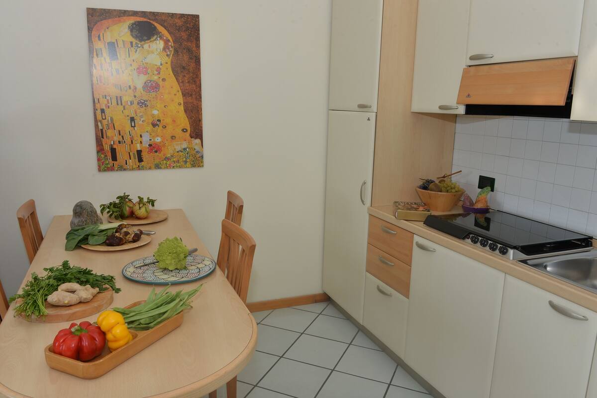 A kitchen with a dining table set for a meal, a refrigerator, and a stove.