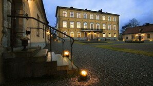 A historic building with a courtyard, steps leading to the entrance, and outdoor lighting. - Ulfsunda Slott (Bromma)