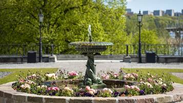 Ein Brunnen mit einer Fischskulptur, umgeben von einer kreisförmigen Steinbordura und floralen Dekorationen.