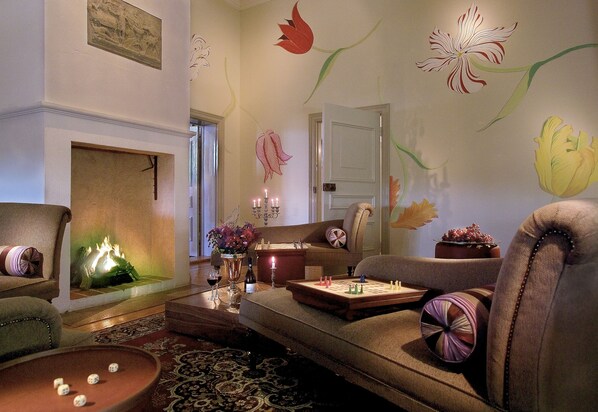 A cozy living room with a fireplace, comfortable seating, and decorative wall art.