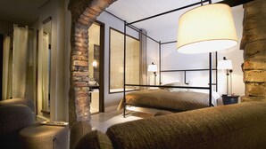A cozy bedroom with a bed, two bedside tables, a hanging lamp, and a brick wall. - Ulfsunda Slott (Bromma)