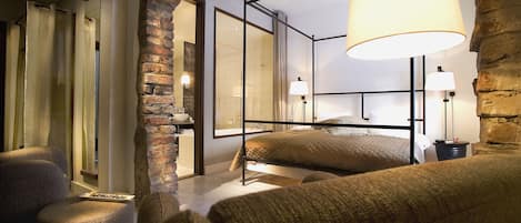 A cozy bedroom with a bed, two bedside tables, a hanging lamp, and a brick wall.