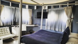 A bedroom with a bed, a desk, a chair, and curtains. - Hotel Terranostra (Valparaiso)