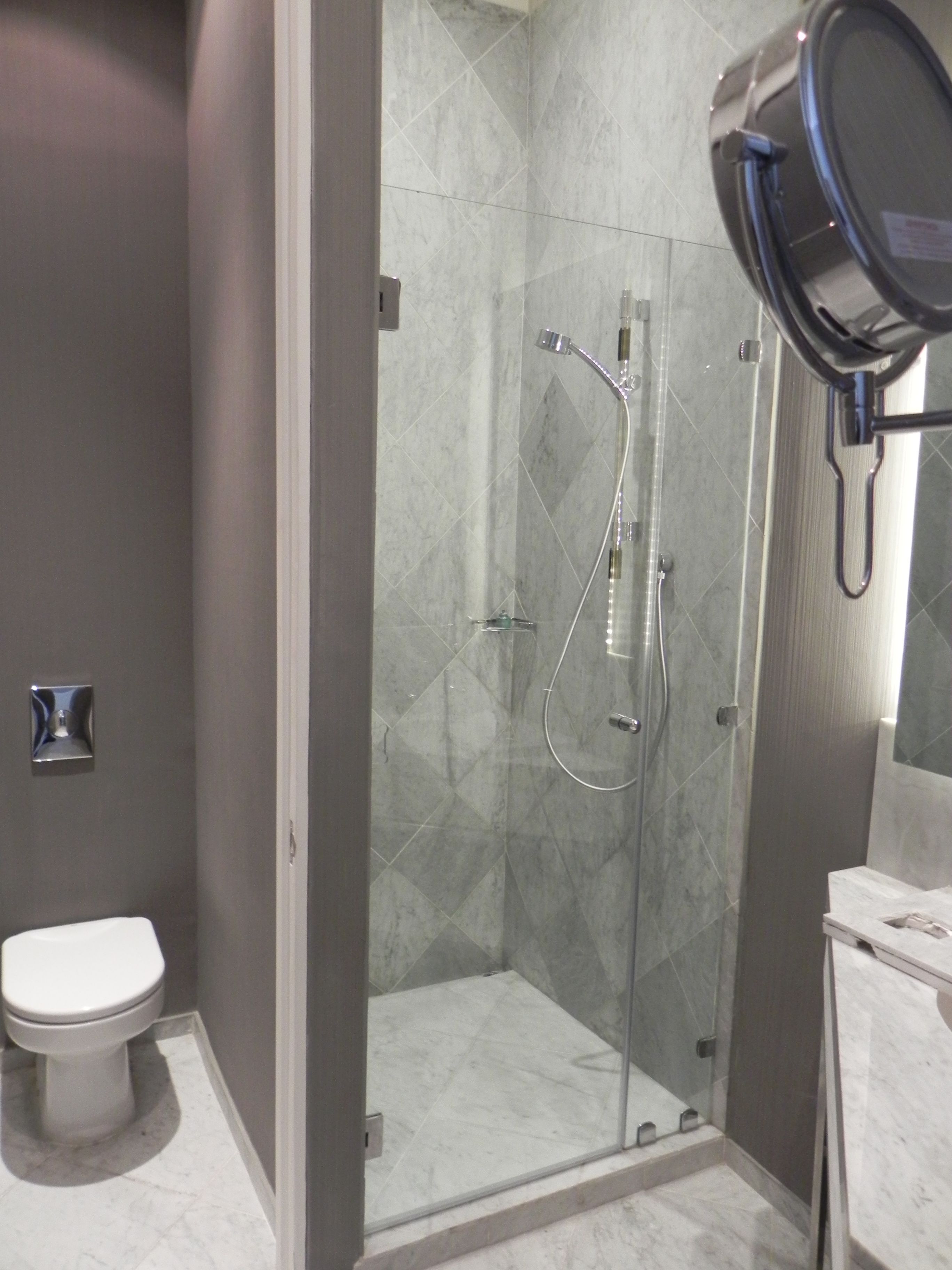 Un baño moderno con ducha envuelta en vidrio, inodoro y tocador con espejo.