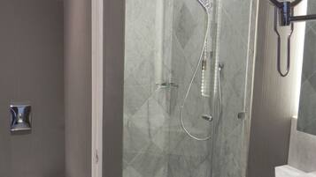Un baño moderno con ducha envuelta en vidrio, inodoro y tocador con espejo.
