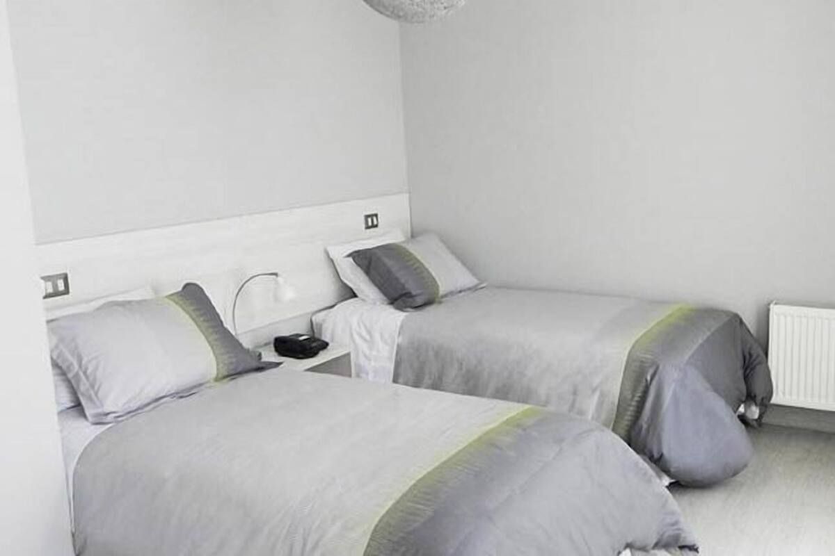 A twin room with two beds, a bedside table, and a radiator.