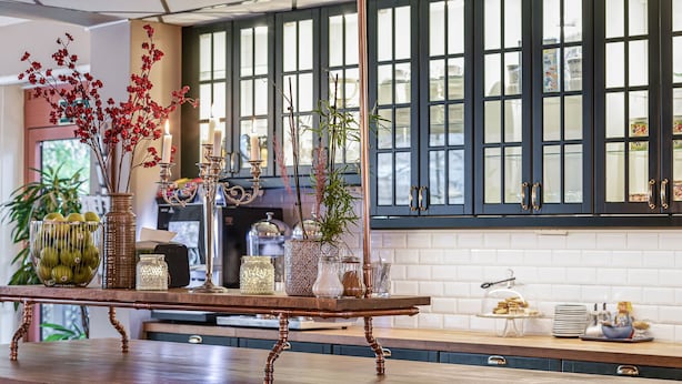 A kitchen with a wooden island, various kitchenware, and decorative plants. - Hotell Arkad (Vasteras)