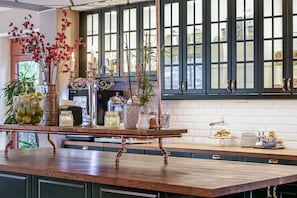 A kitchen with a wooden island, various kitchenware, and decorative plants.