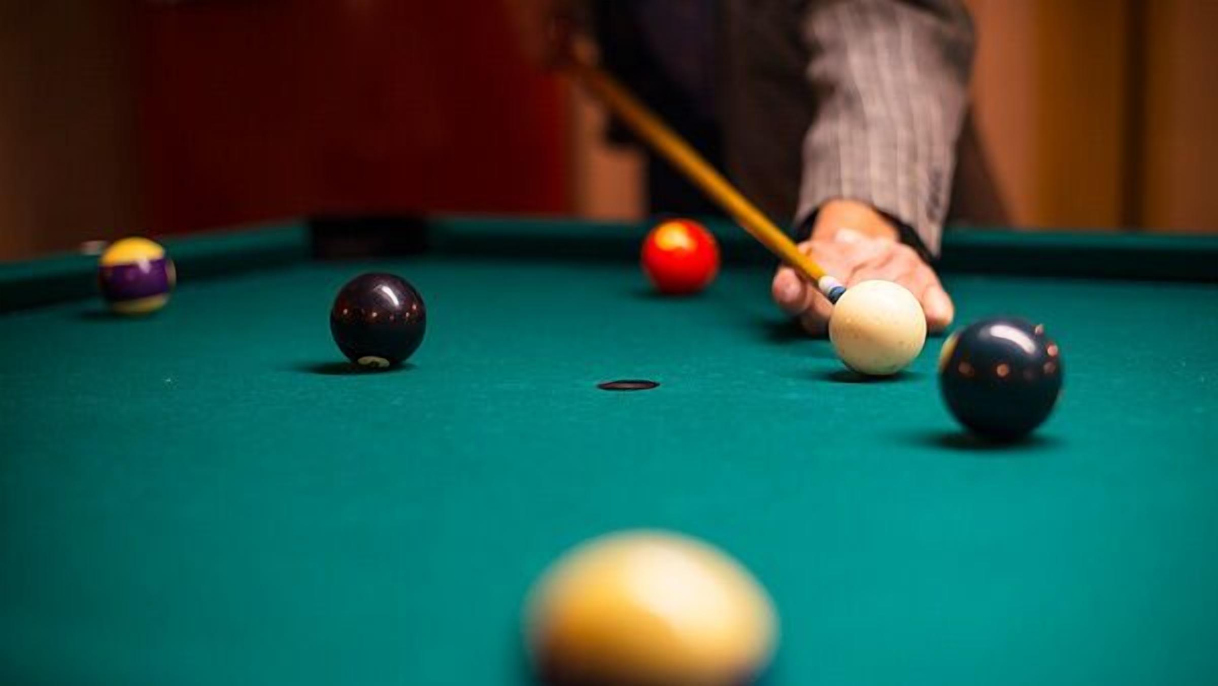 Une table de billard avec des billes et une queue de billard.