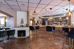 A bar area with a reception desk, bar stools, a fireplace, and a herringbone wood floor. - Hotell Arkad (Vasteras)