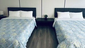 A hotel room with two beds, each with a dark headboard and white bedding. There is a small table between the beds with a plant on it. - Hope City Centre Motel (Hope)