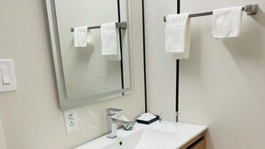 A bathroom with a white sink, wooden vanity, a mirror, and two towel racks. - Hope City Centre Motel (Hope)