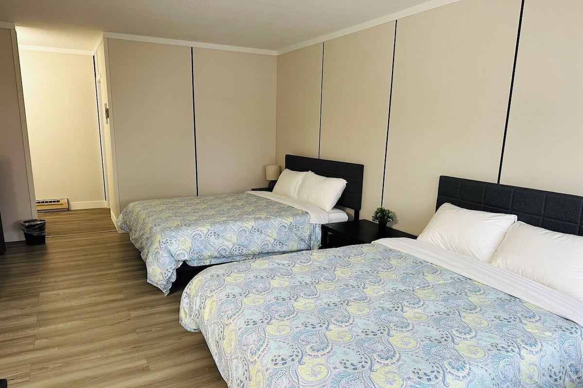 A hotel room with two beds, wooden flooring, and a simple, clean design.