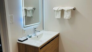 A modern bathroom with a white sink, wooden vanity, and a mirror with integrated lighting. - Hope City Centre Motel (Hope)