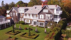 Ein großes, mehrgeschossiges Haus mit großem Vorgarten und überdachter Veranda.