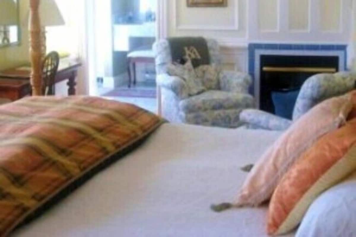 Une chambre à coucher comprenant un lit, une chaise, une cheminée et une porte donnant sur une autre pièce.