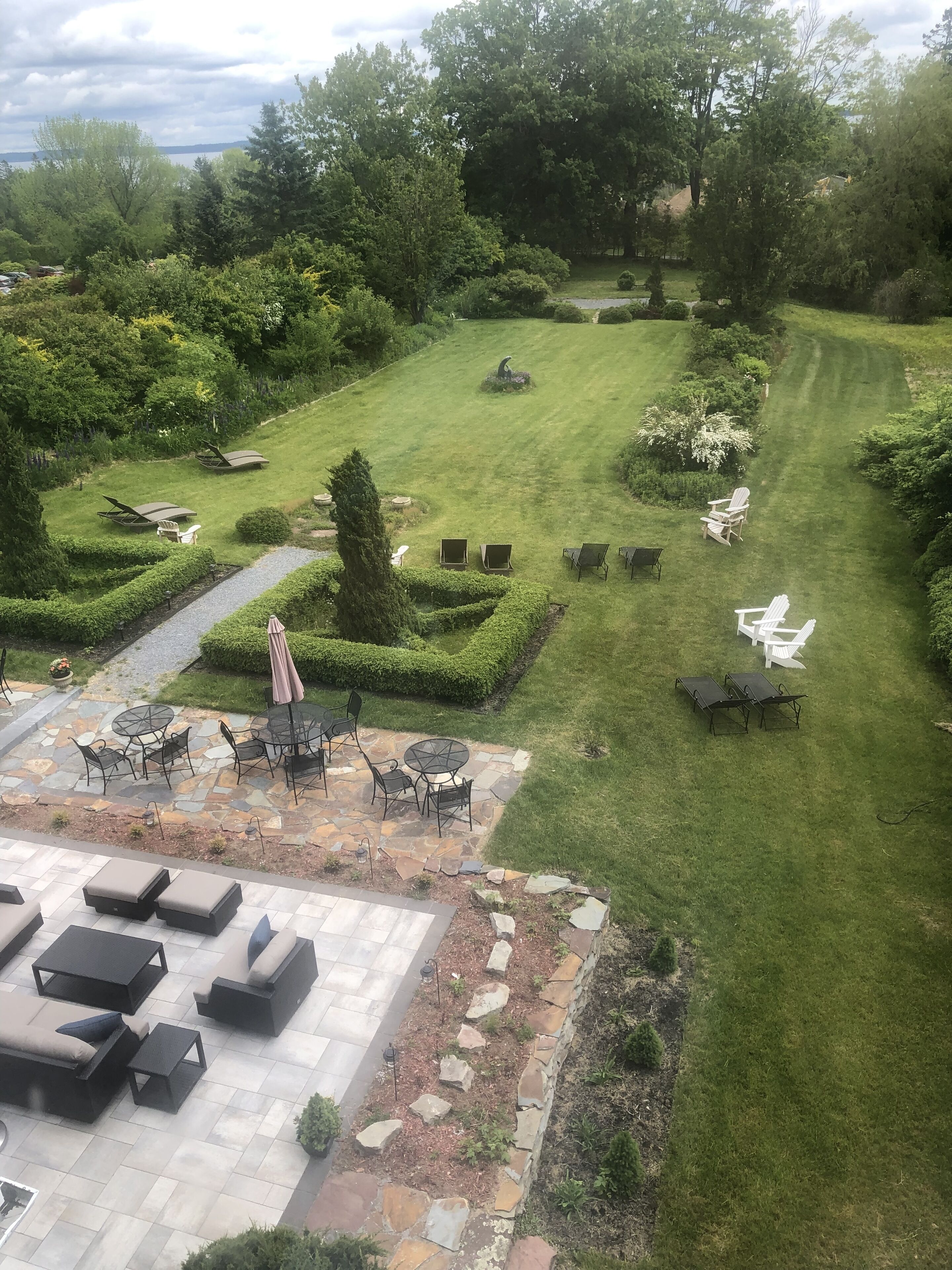 A well-maintained garden with a lawn, seating areas, and a stone patio.