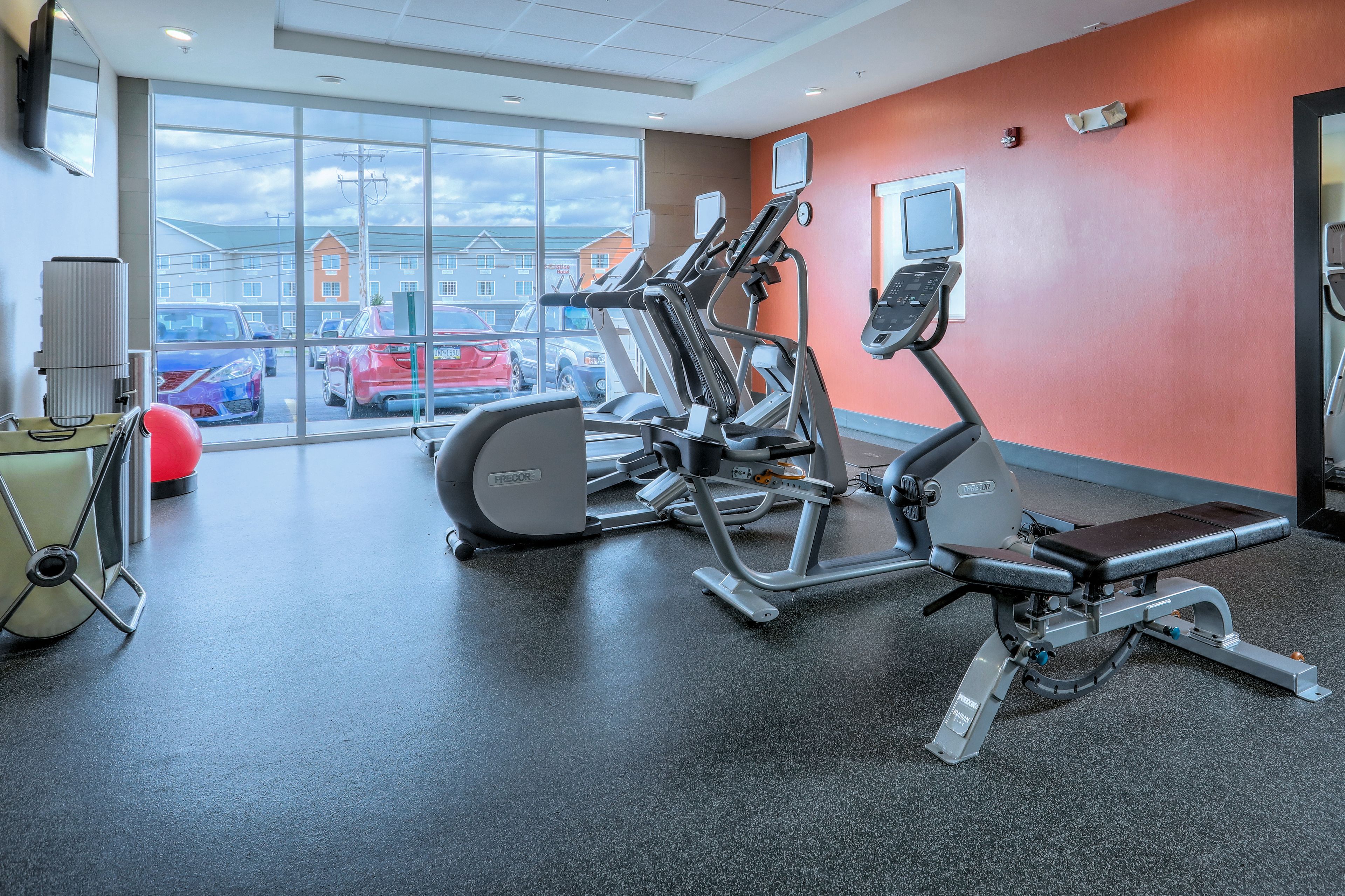 Un gimnasio con cintas de correr, elípticas y una bicicleta estática.