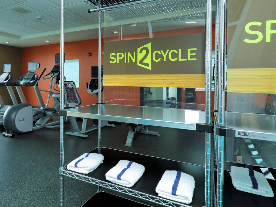 A gym with treadmills, stationary bikes, and a wall sign reading "SPIN2CYCLE".