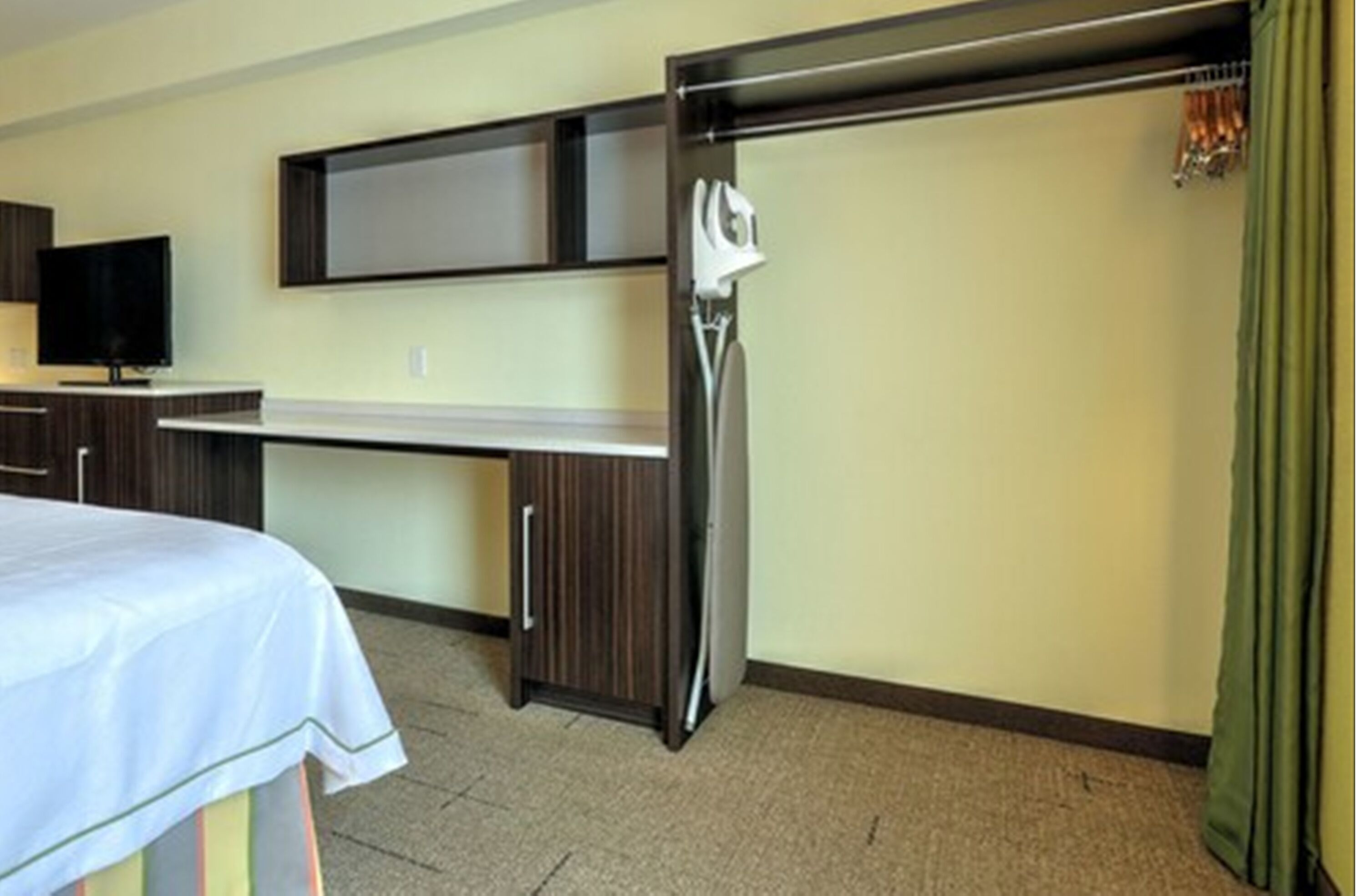 Una camera d'hotel con un letto, una scrivania, una TV a schermo piatto, un minibar e un armadio.