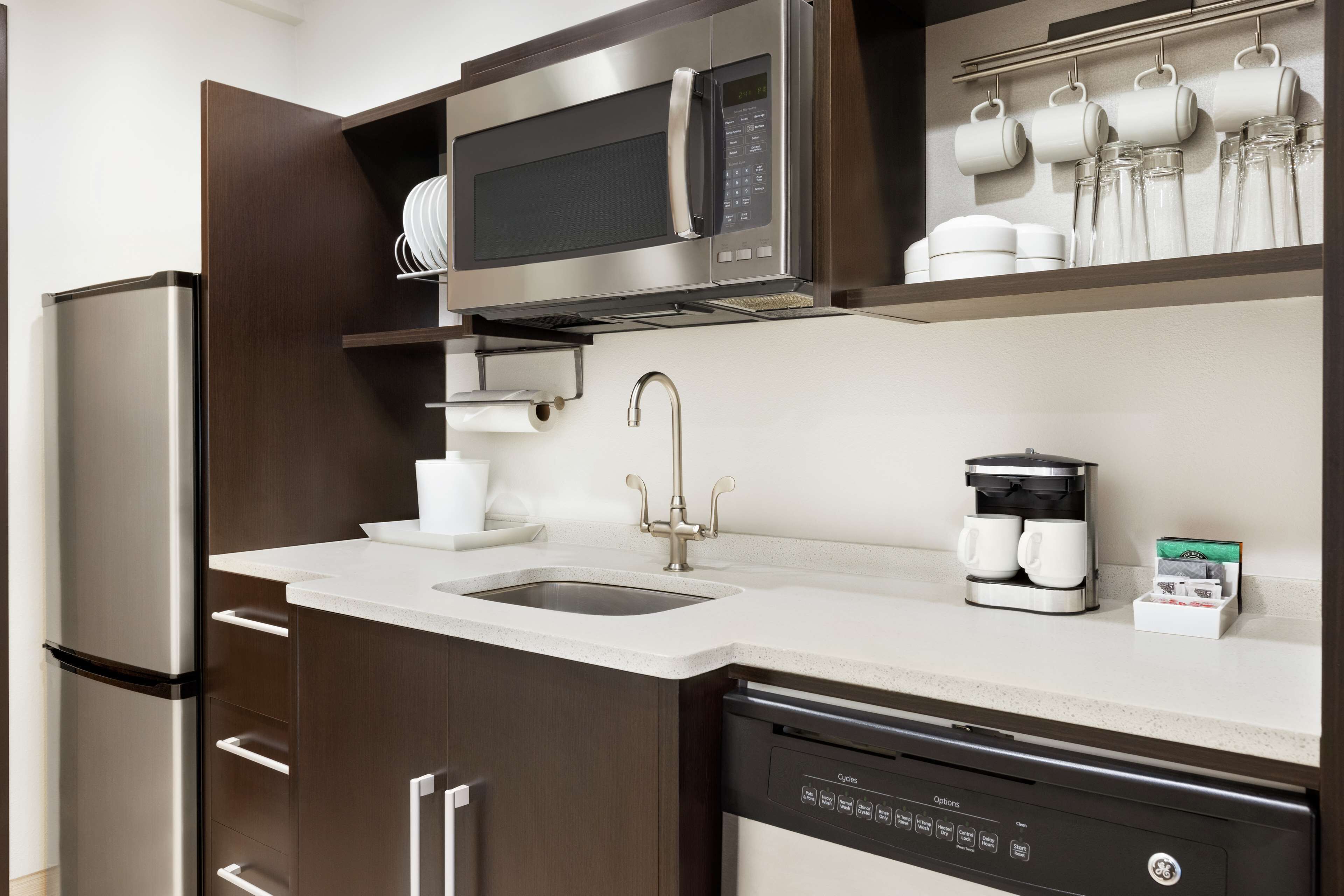 A modern kitchen with a built-in microwave, coffee maker, and dishwasher.