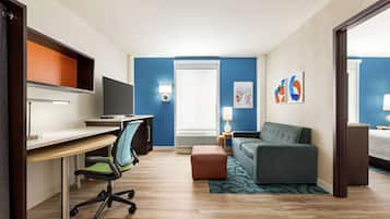 A hotel room with a desk, chair, couch, and a bed.