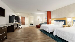 Habitación de hotel con dos camas, un escritorio, una silla y un televisor.