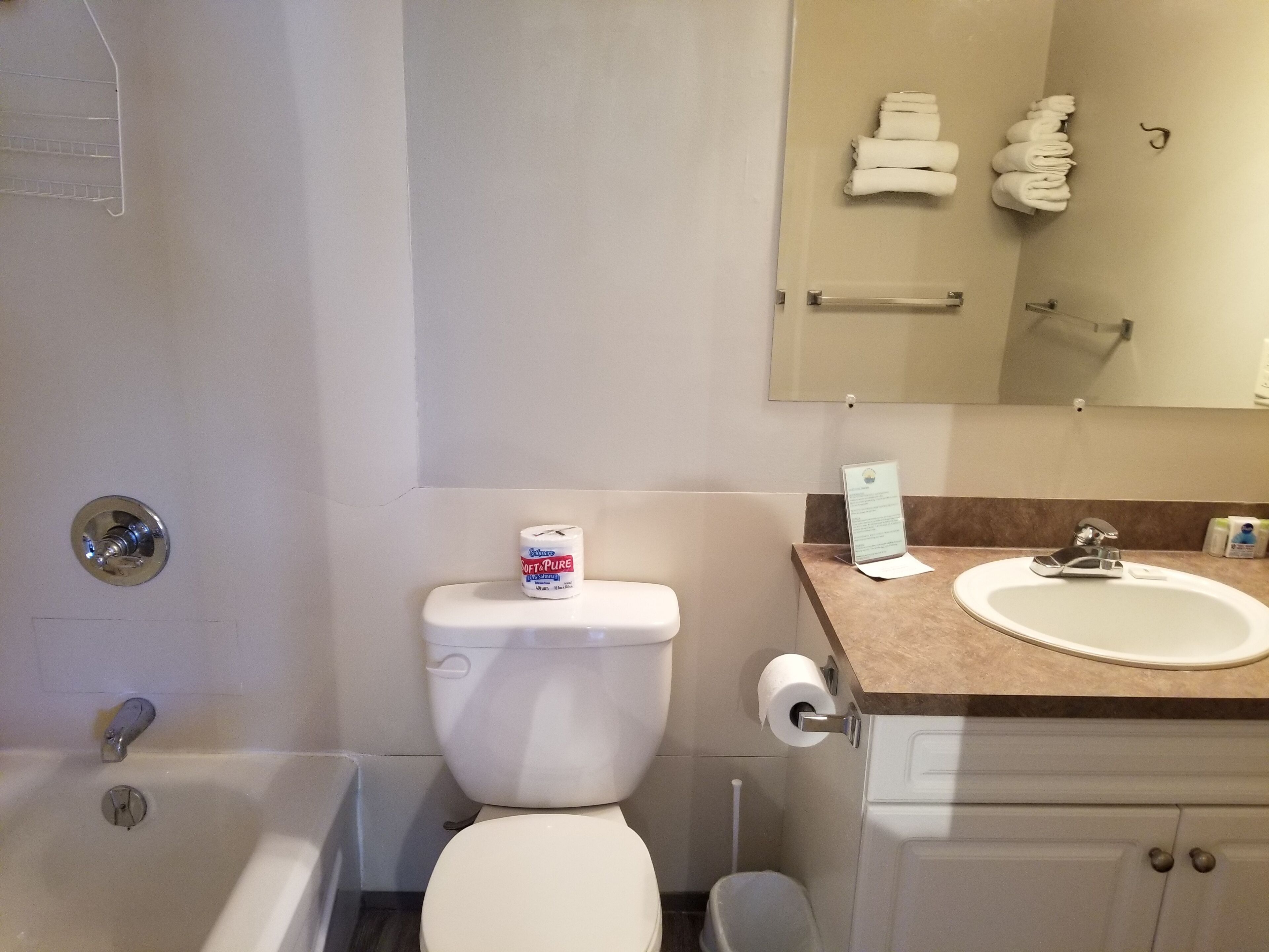 Un baño con bañera, inodoro, lavamanos y espejo con toallas.