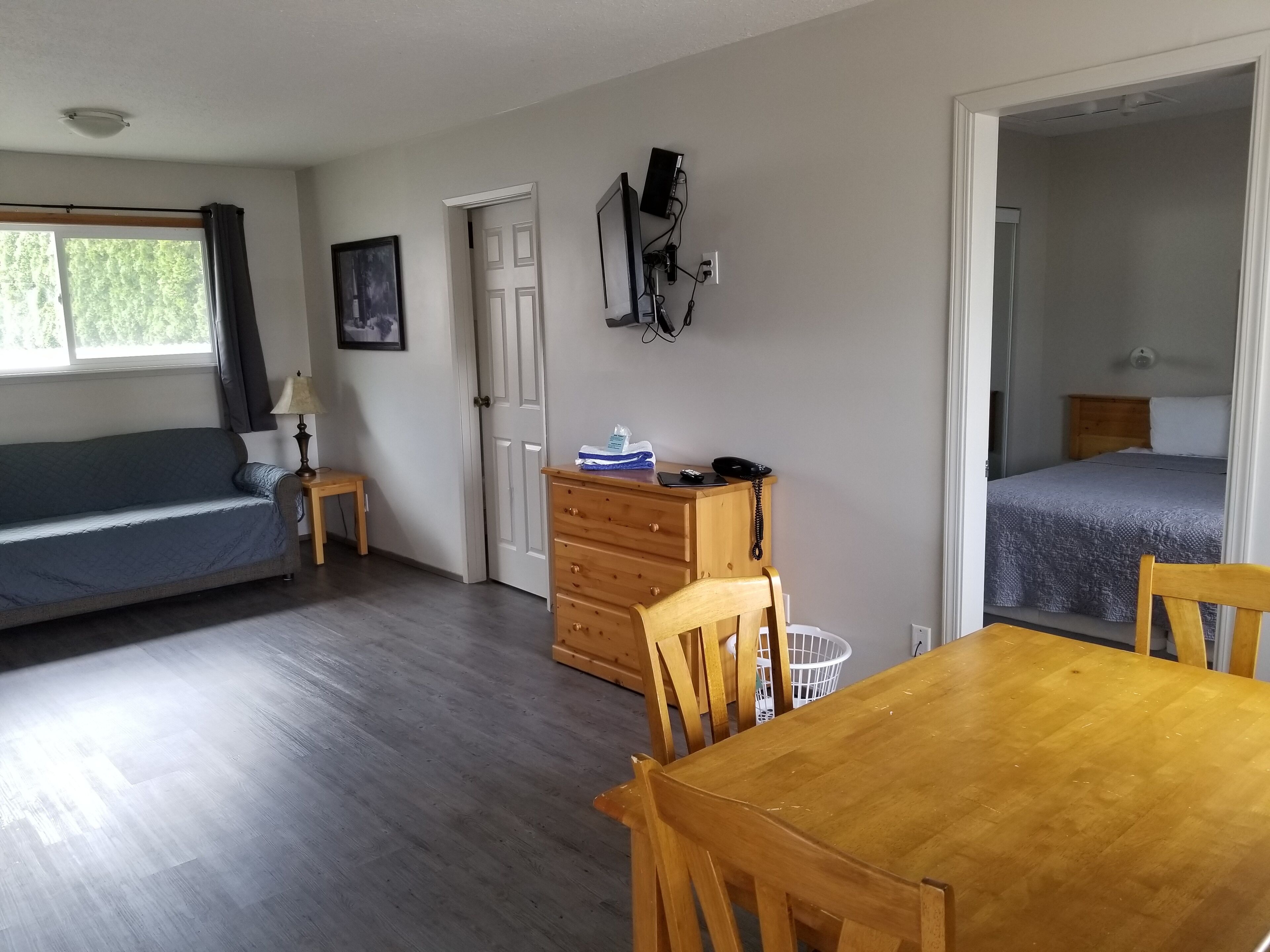 Ein Zimmer mit Bett, Schreibtisch, Stuhl, Tisch und Fenster.