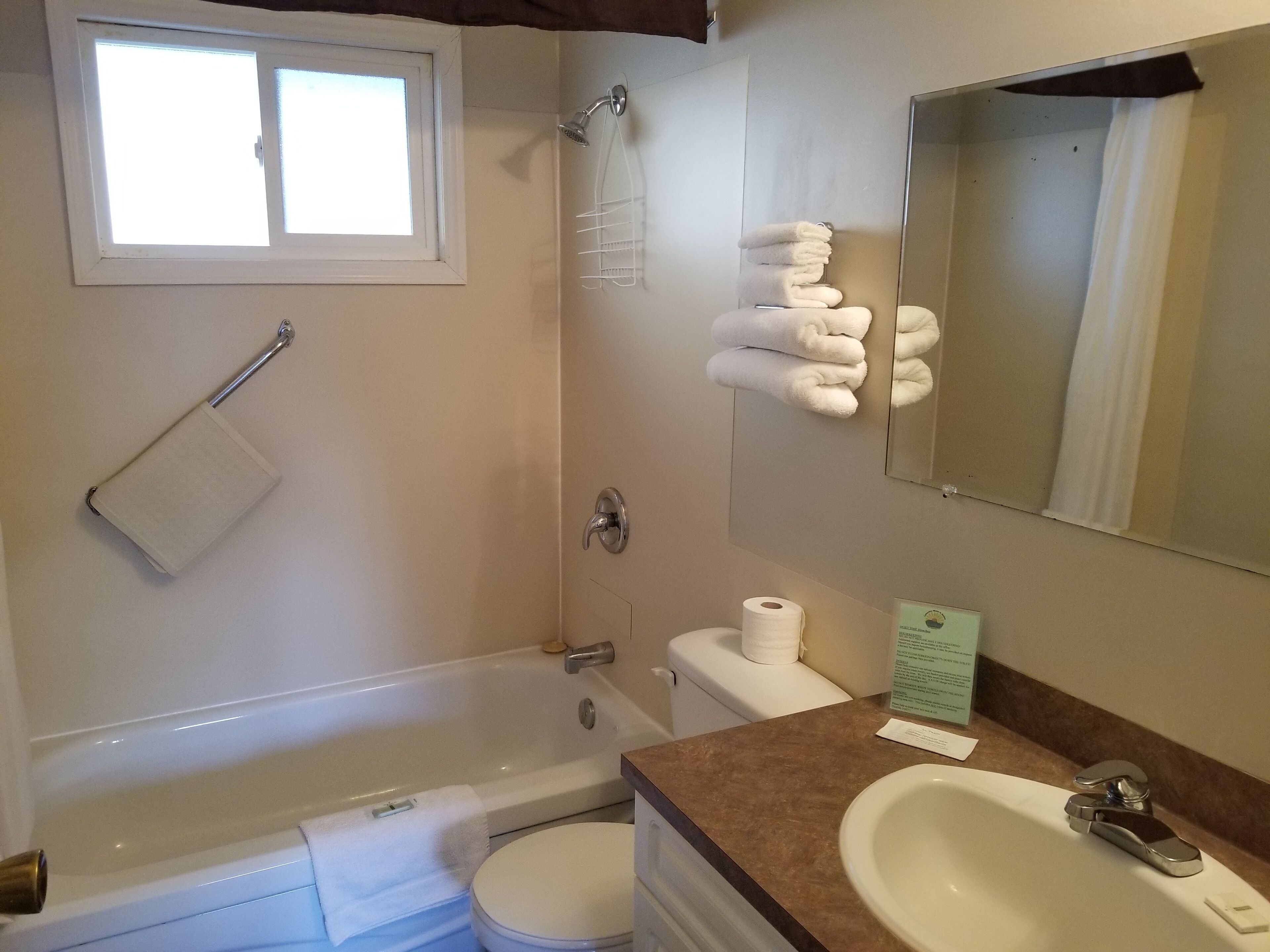 A bathroom with a bathtub, toilet, sink, and a towel rack with towels.