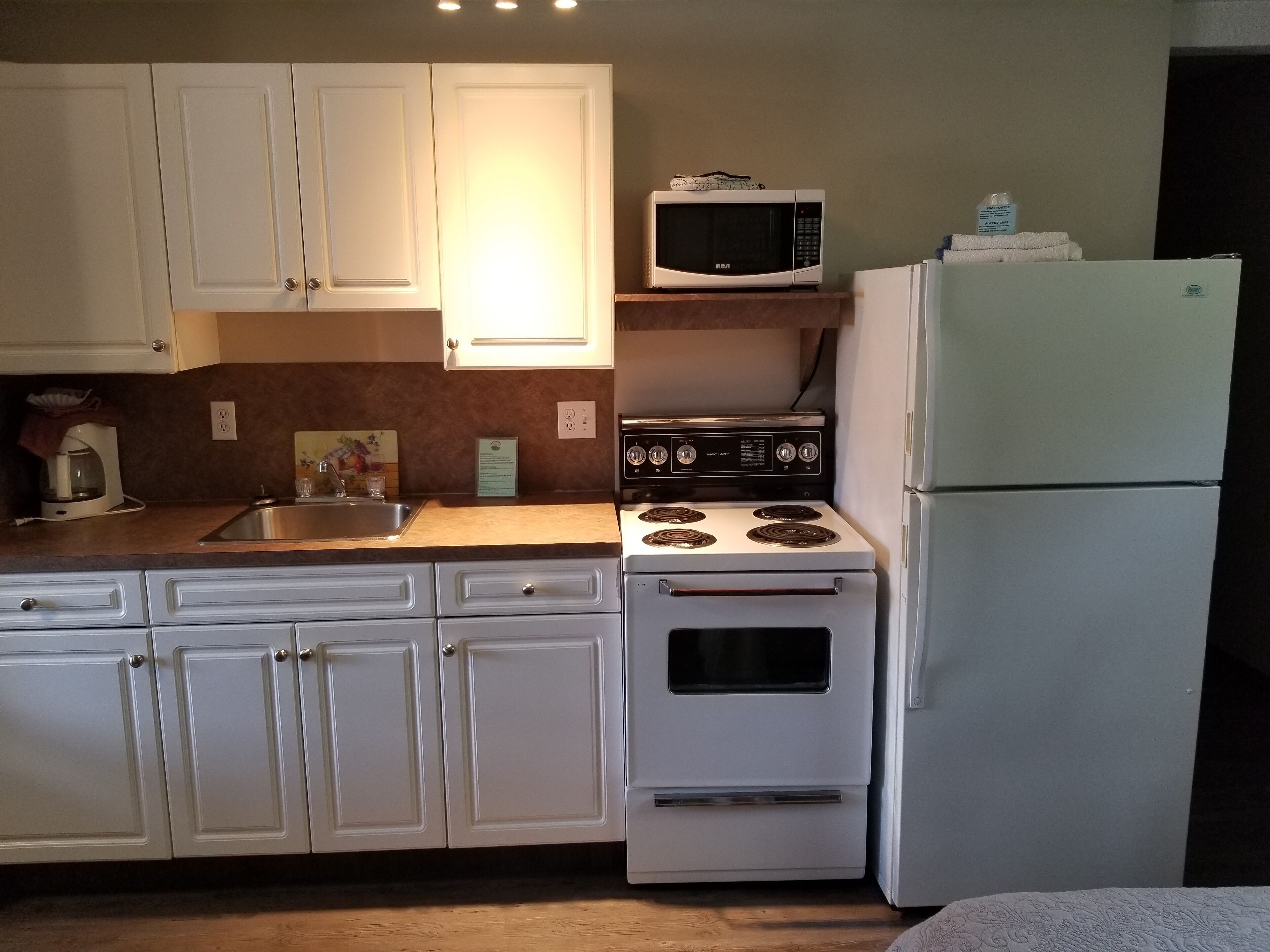 A kitchen with white cabinets, a microwave, stove, and refrigerator.