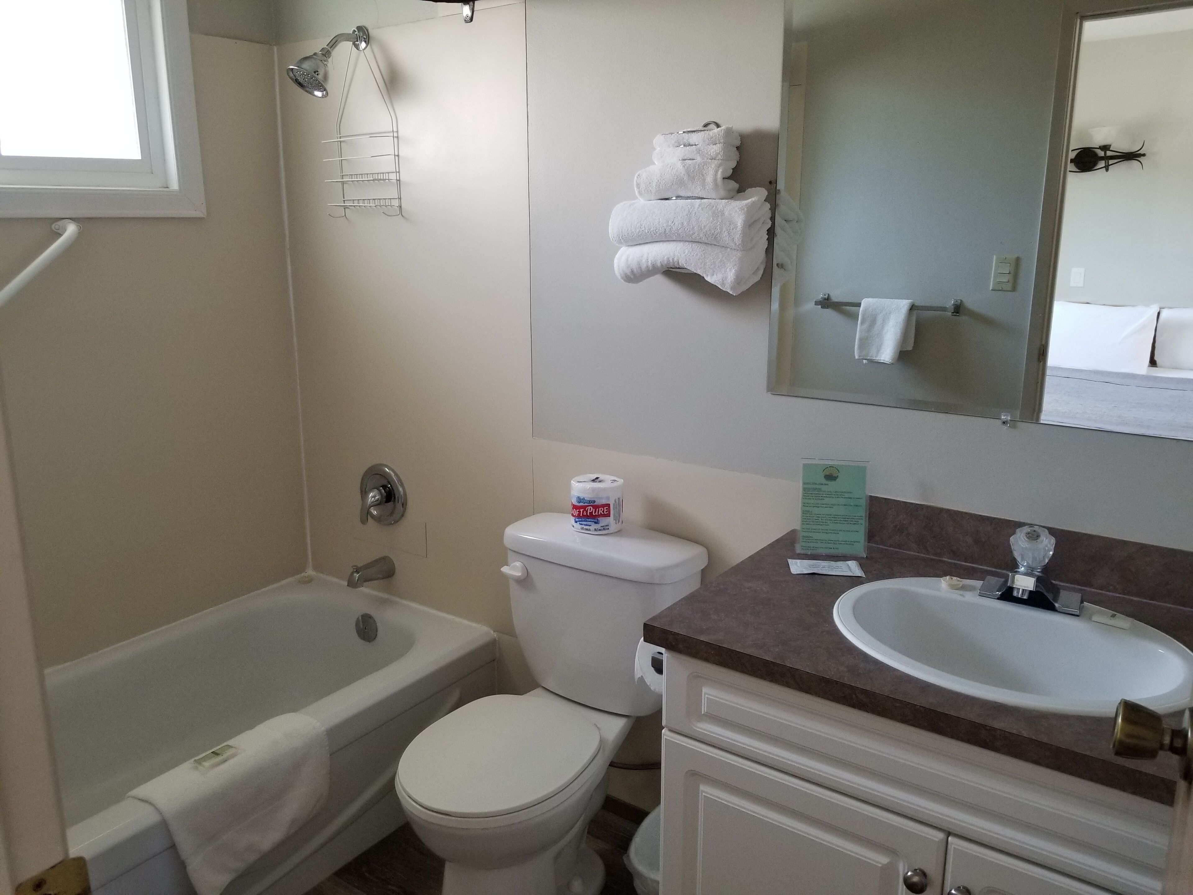 A bathroom with a bathtub, toilet, sink, and a mirror.